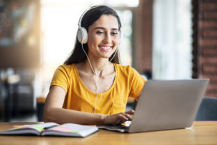 Smiling arab girl with headset studying online, using laptop