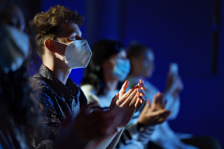 Group of people clapping while listening to presentation at conference, coronavirus concept.