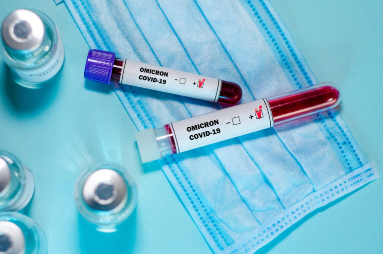 Test tube with positive Omicron COVID 19 test blood sample and vaccine bottle in the medical laboratory.