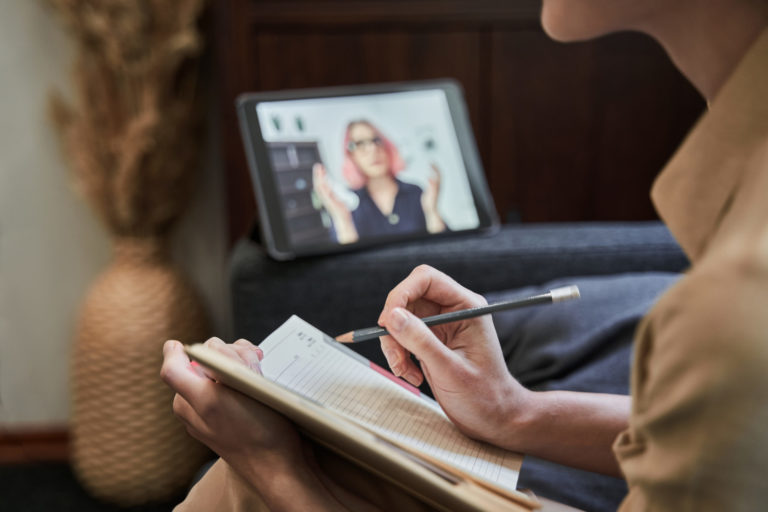 Female psychotherapist is holding a notebook and making notes during the online session