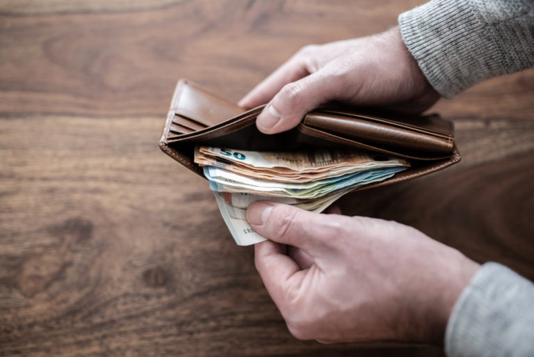 Close up of person counting stack of paper cash in wallet