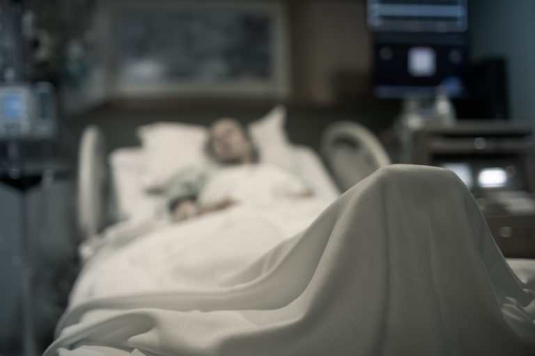 Stressed sick woman lying in hospital bed getting medical treatment.