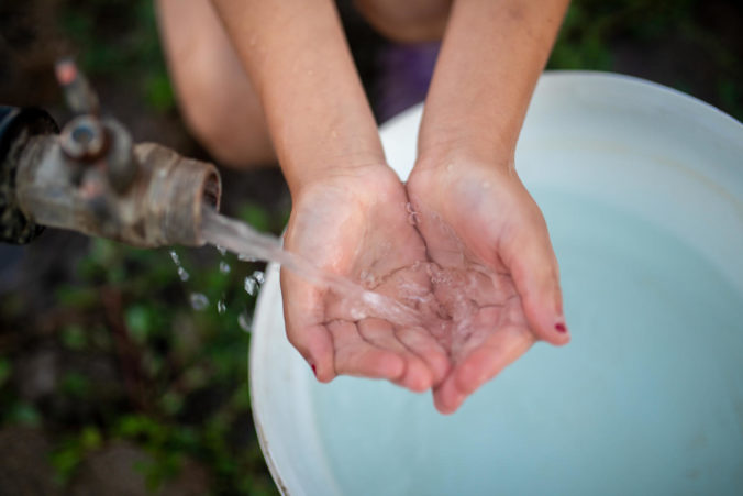Dasha, eight, a child living in Pavlopil, washes her hands while filling a bucket with safe water provided by UNICEF. Dasha lives in the village with her younger sister, Katia, and grandmother, Valentyna. A water pipe passes through their garden; however,