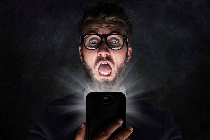 Nerd with glasses is shocked after reading a sms