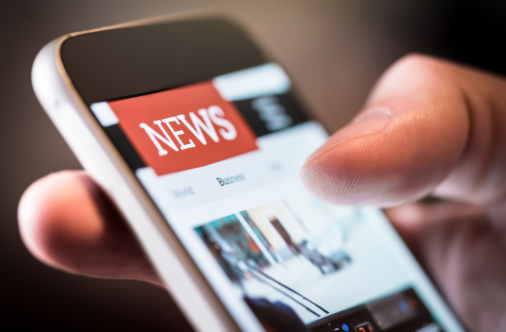 Online news in mobile phone. Close up of smartphone screen. Man reading articles in application. Hand holding smart device. Mockup website.