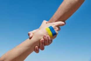 Lend a hand help painted in ukrainian flag colors against blue sky. Stand with Ukraine