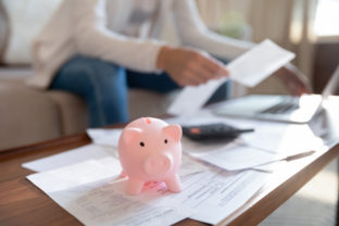 Cute piggybank standing on home office desk littered with documents