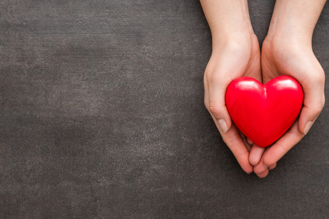 The woman is holding a red heart.