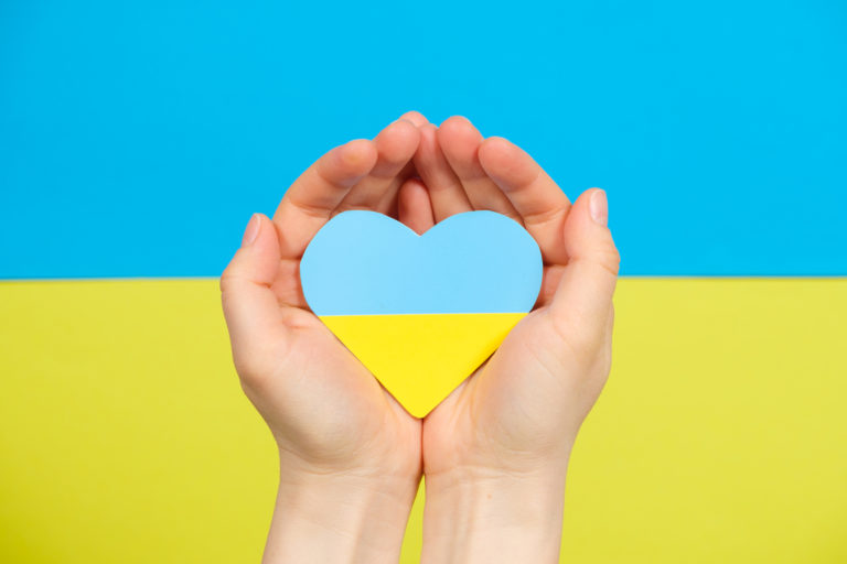Yellow blue heart in the color of the flag of Ukraine in the hands of a person, a place for text. Love for one's country, Constitution Day and Independence Day