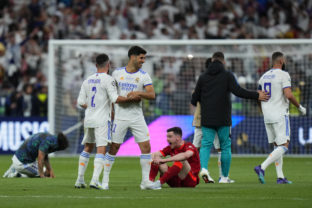 Liverpool's Andrew Robertson, center, is dejected as Real players celebrate after the Champions League final soccer match between Liverpool and Real Madrid at the Stade de France in Saint Denis near Paris,
