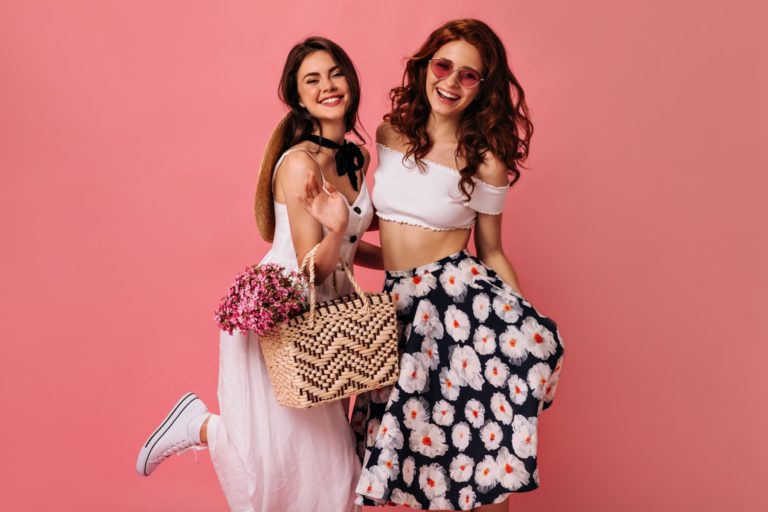 Happy lady in stylish skirt and boater posing on pink background. Young woman in colorful skirt and