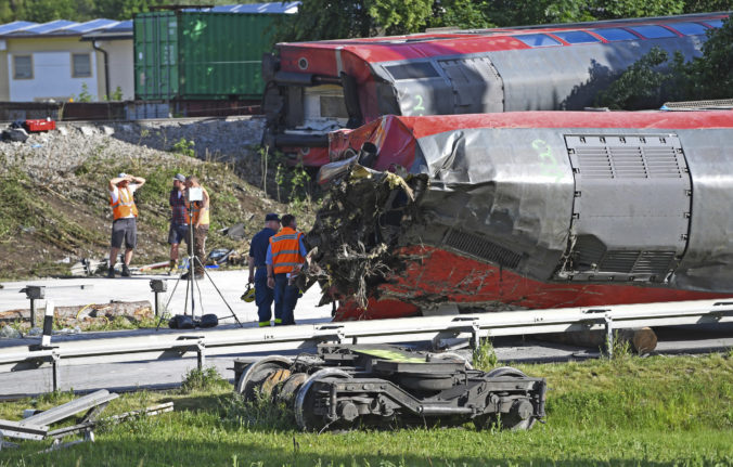 Persons of the German rail operator Deutsche Bahn' stead next to a carriage on the site of a train crash in Burgrain, near Garmisch-Partenkirchen, Germany, Sunday June 5, 2022. Police said the regional train headed for Munich appears to have derailed shortly after noon in Burgrain, just outside the resort town of Garmisch-Partenkirchen, from where it had set off.