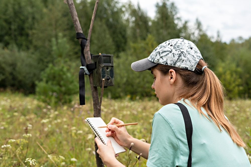 Young,Woman,Scientist,Zoologist,Writing,Down,Data,From,Trap,Camera