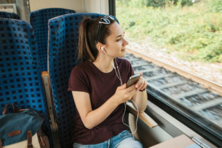A young girl listens to a music or podcast while traveling in a train