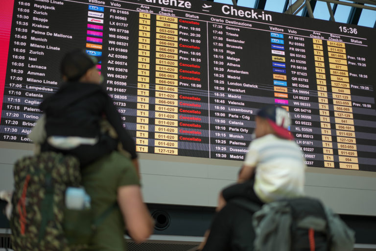 Passengers look at flights timetables in Rome's Leonardo Da Vinci international airport, Sunday, July 17, 2022. Several hundred flights were canceled in Italy Sunday, a peak vacation travel day, because of four-hour walkouts involving employees of low-cost airlines as well as air traffic controllers