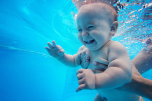 Baby background. Happy infant learn to swim, dive underwater wit