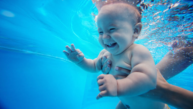 Baby background. Happy infant learn to swim, dive underwater wit