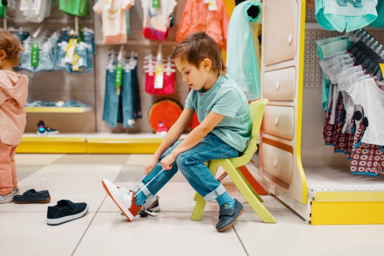Little boy trying on shoes in kids store