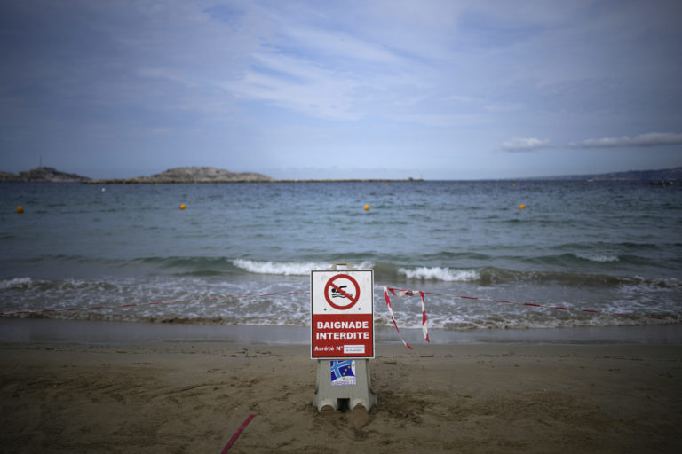 A sign reading "swimming prohibited" sits on a beach with high levels of pollution the morning after a storm passed through Marseille, southern France