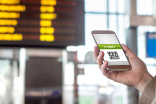 Buying online ticket from internet. E ticket on mobile phone screen with schedule in the blurred background. Universal public transportation terminal. Bus, train, metro, subway or underground station
