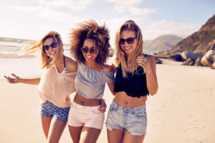 Portrait,Of,Three,Young,Female,Friends,Walking,On,The,Sea