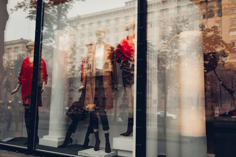 Manikins dressed in autumn outfits on showcase of a store in city center. Shopping and sales concept