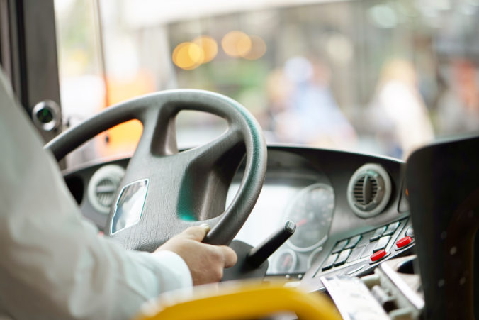 Cropped shot of bus driver holding steering whee