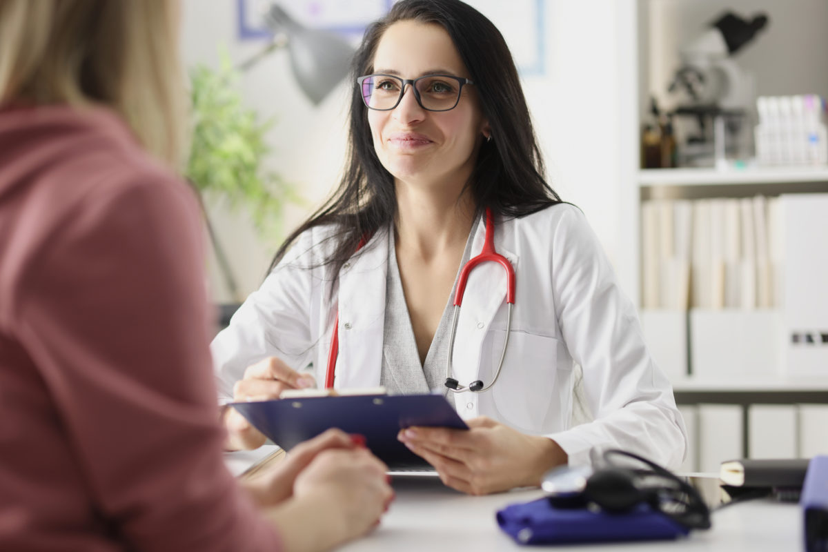 Happy smiling woman doctor is receiving patient at clinic