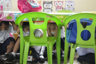 Students duck under a table during an earthquake drill at an elementary school in Metro Manila, Philippines on Thursday Sept. 8, 2022. The Philippines conducted its third quarter nationwide earthquake drill as part of efforts to make the public aware of protocols and response during a disaster
