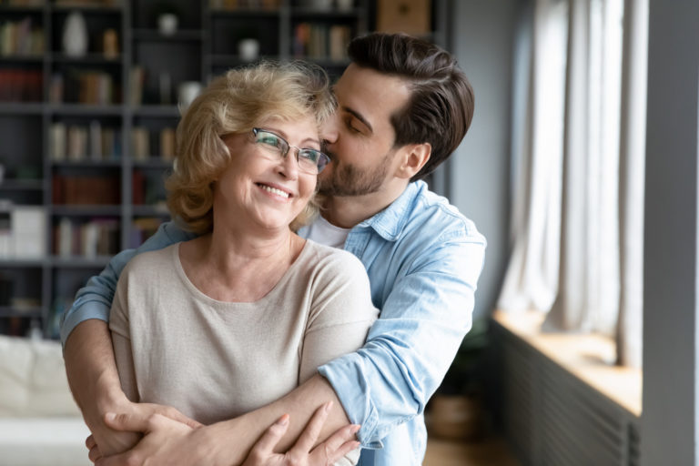 Loving adult son kissing and hugging happy mature mother