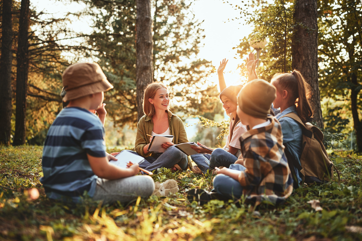 Pôdohospodárska platobná agentúra les ekosystem Kids raising hands asking questions during outdoor lesson with t