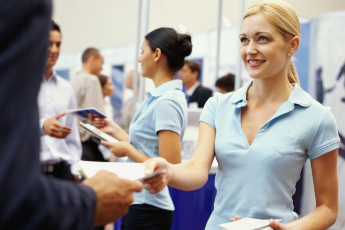 Sales executives distributing brochures to business executives at an exhibition