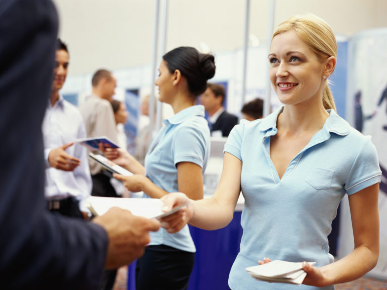 Sales executives distributing brochures to business executives at an exhibition