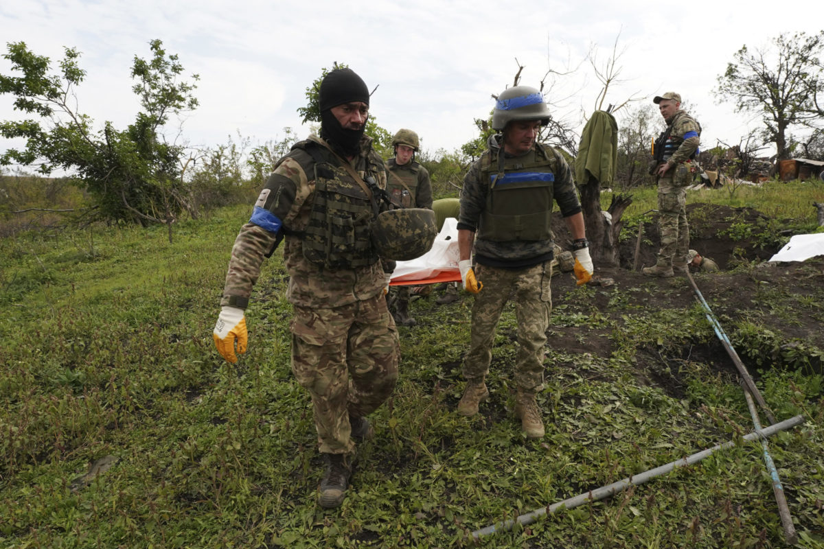 Ukrainian soldiers carry a body of their comrade-in-arms killed in a battle against the Russian troops in the Kharkiv region, Ukraine