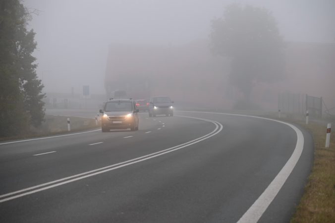 Car on the road in the fog. Autumn landscape - dangerous road traffic in winter season.