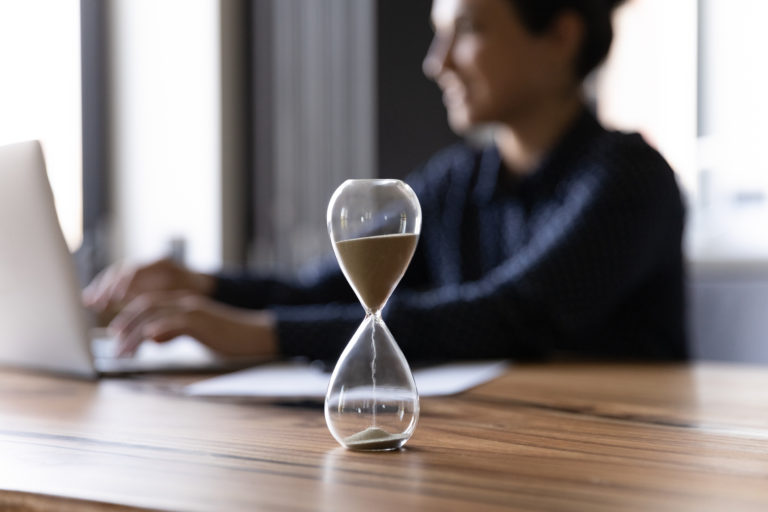 Close up hourglass measuring time, Indian businesswoman working