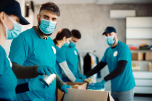 Group people with protective face masks packing donation boxes food charity.jpg
