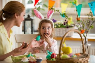 Mother and daughter celebrating Easter, eating chocolate eggs. H