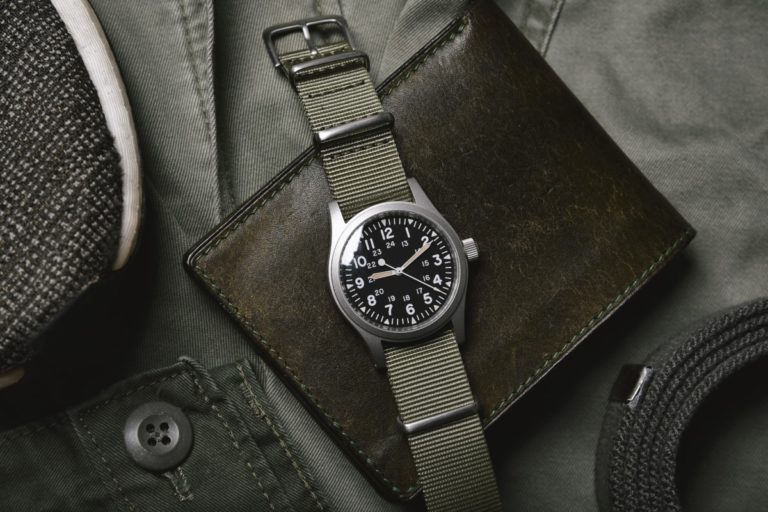 Vintage military watch with nato strap and leather wallet on army green background, Classic timepiece mechanical wristwatch, Military men fashion and accessories.