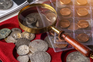 Numismatics. Old collectible coins made of silver on a wooden table.Coins in the album.Collection of old coins. Magnifying glass