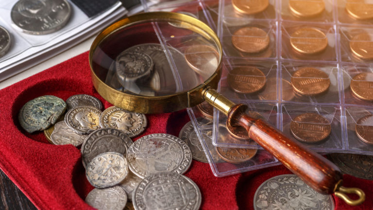 Numismatics. Old collectible coins made of silver on a wooden table.Coins in the album.Collection of old coins. Magnifying glass