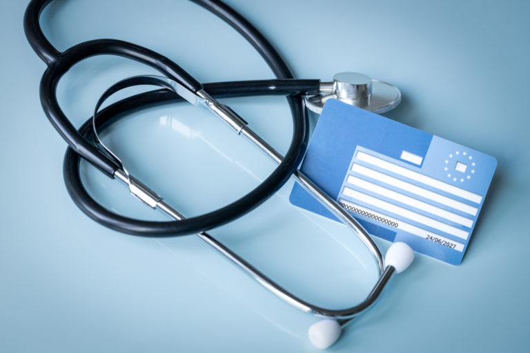 European health insurance card next to a medical stethoscope. Concept, EU document confirming the right to treatment outside the country, Travel insurance. Holiday insurance for Europeans.