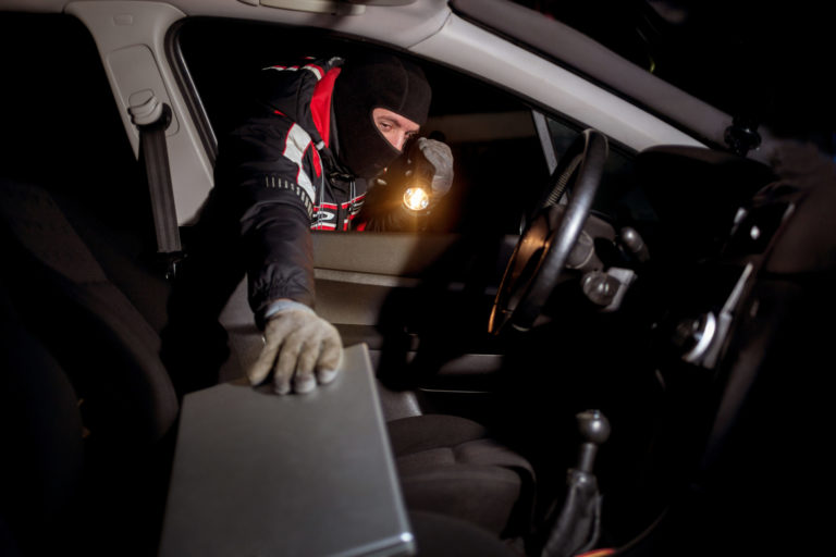 Robber breaking a car's  to steal a lap top