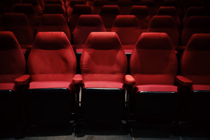 Interiors of empty comfortable red cinema chairs. Low key. Dark tone.