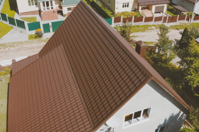 Brown metal tile on the roof of the house. Corrugated metal roof