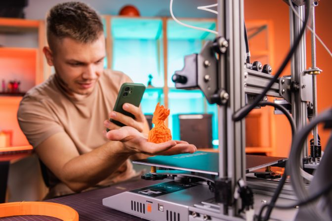 Student in the workshop photographs a part preprinted on a 3D printer