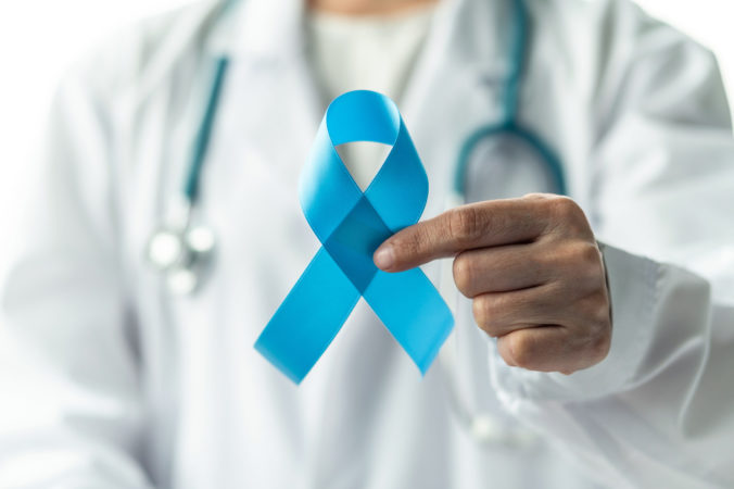 Prostate cancer blue awareness ribbon for men health in November with light blue bow color on medical doctorâs hand in clinical lab gown in hospital, male patient healthcare concept