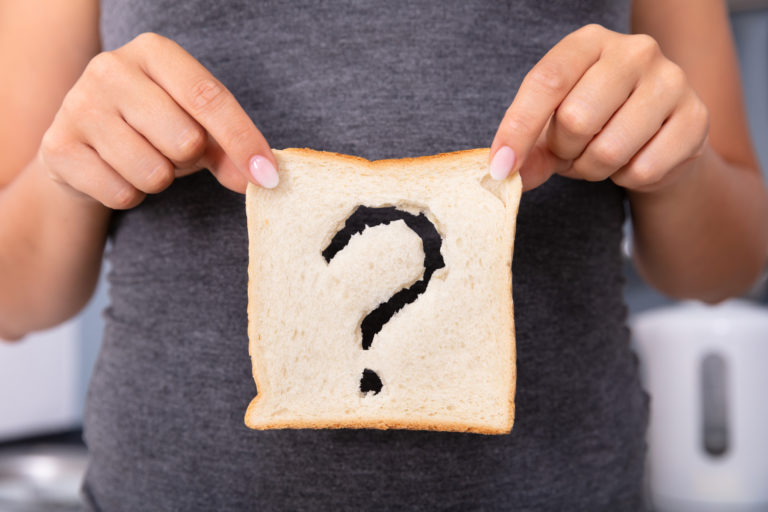 Woman Holding Slice Of Bread With Question Mark Sign