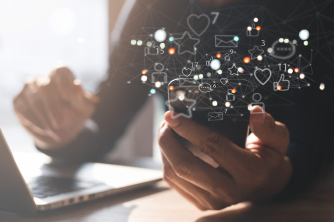 Man using mobile phone at home with social media apps icons on virtual screen, social media, digital marketing