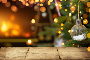 Empty wooden table on Christmas ornaments background with fireplace. Copy space.